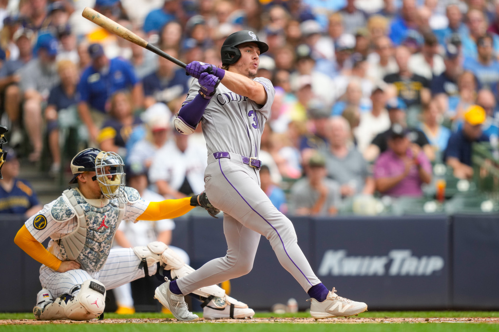 Colorado Rockies' Jake McCarthy hits a triple as Milwaukee Brewers catcher William Contreras, left, looks on during the third inning of a baseball game Friday, July 24, 2026, in Milwaukee. (AP Photo/Kayla Wolf)