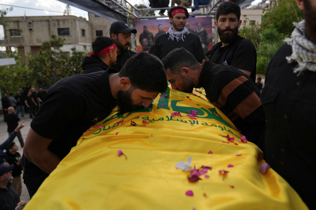 Mourners kiss a coffin of a Hezbollah fighter, who was killed before the ceasefire in the war between Hezbollah and Israel, during a mass funeral procession in the southern village of Kfar Sir, Lebanon, Tuesday, April 21, 2026. (AP Photo/Hassan Ammar)