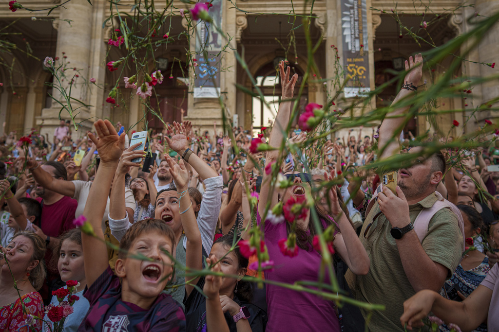People throw carnations during an event marking the day when the Romanian capital was first mentioned in historical records, 566 years ago, in Bucharest, Romania, Saturday, Sept. 20, 2025. (AP Photo/Vadim Ghirda)