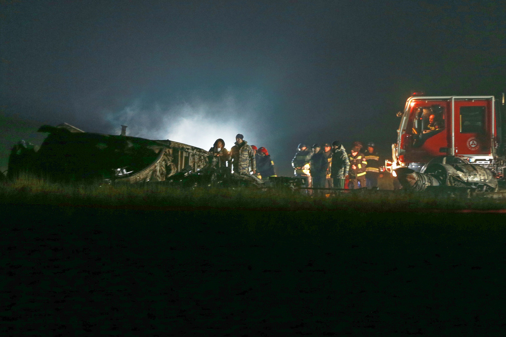 Investigators and emergency workers stand next to debris at a crash site of a Turkish military cargo plane in Georgia's Sighnaghi municipality, close to the Azerbaijani border on Wednesday, Nov. 12, 2025. (AP Photo/Zurab Tsertsvadze)