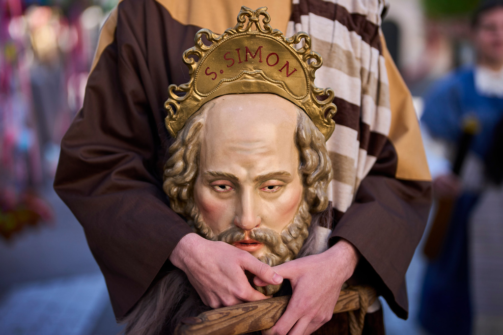 A penitent of the 'Pollinita' brotherhood, dressed in a typical Apostle costume, holds an image symbolizing the apostles during the Holy Week procession in Cabra, southern Spain, Sunday, March 29, 2026. (AP Photo/Manu Fernandez)
