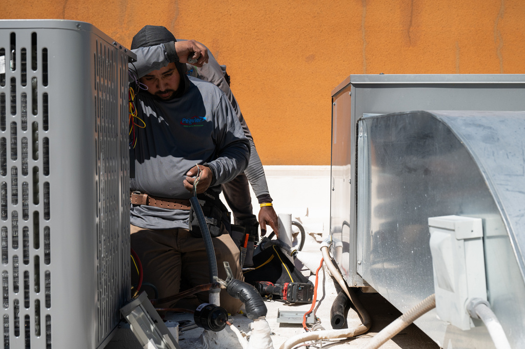 Brian Hermosillo wipes sweat from his brow while installing a new air conditioning unit during record-breaking heat Thursday, March 19, 2026, in Tempe, Ariz. (AP Photo/Caitlin O'Hara)