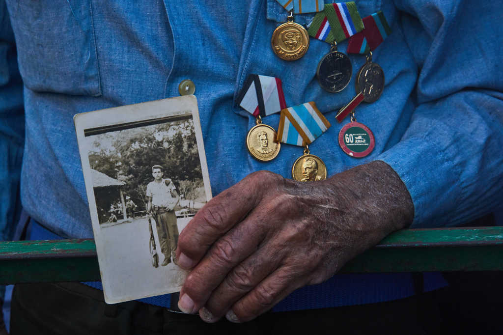 Militiaman Rene Hernandez Delgado holds a photo of his younger self during a celebrations marking the 65th anniversary of the proclamation declaring the Cuban Revolution socialist, in Havana, Cuba, Thursday, April 16, 2026. (AP Photo/Ramon Espinosa)