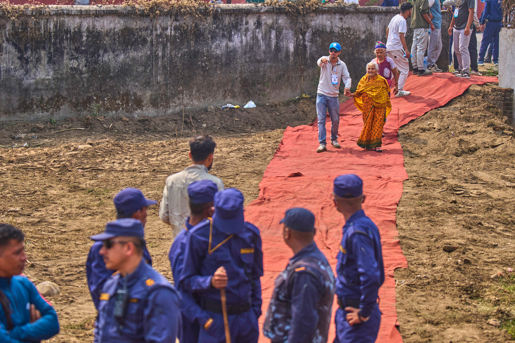A volunteer helps elderly Rastriya Swatantra Party supporters as they arrive for an election campaign rally for rapper-turned-politician Balendra Shah in Chitwan, approximately 180 kilometers (112 miles) west of Kathmandu, Nepal, Friday, Feb. 27, 2026. (AP Photo/Niranjan Shrestha)