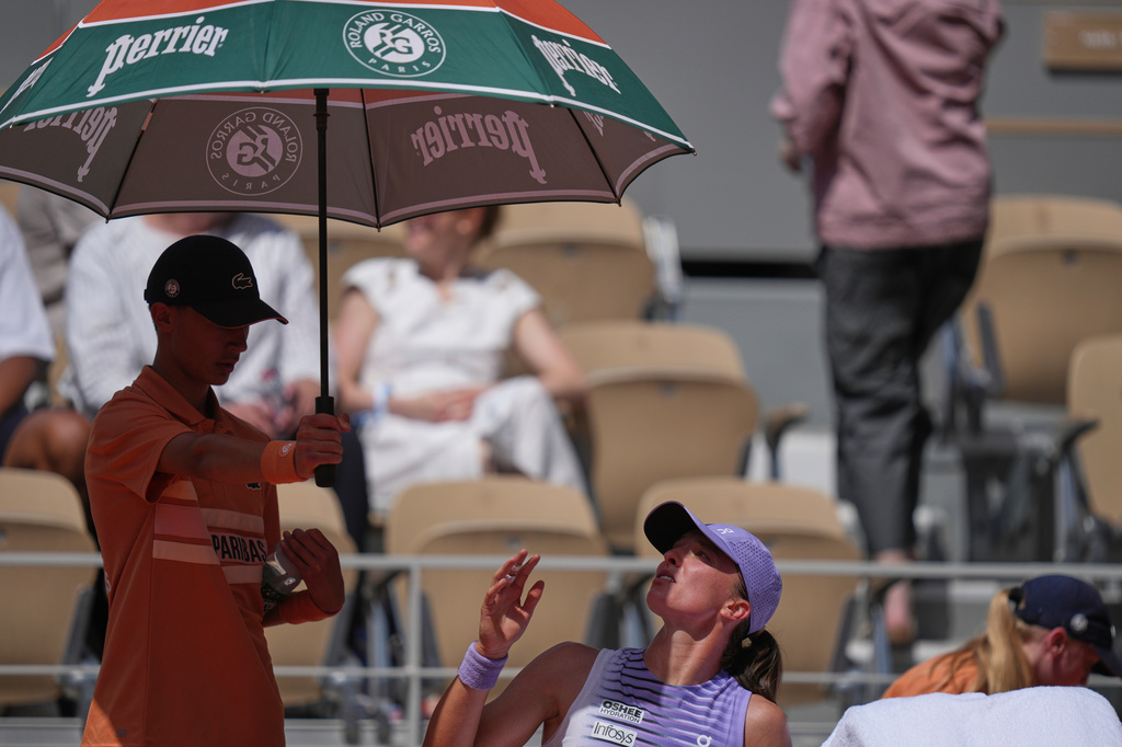 Poland's Iga Swiatek gestures for a ballboy as he shields her from the sun during a break at the first round women's singles tennis match against Emerson Jones of Australia at the French Open tennis tournament in Paris, Monday, May 25, 2026. (AP Photo/Thibault Camus)