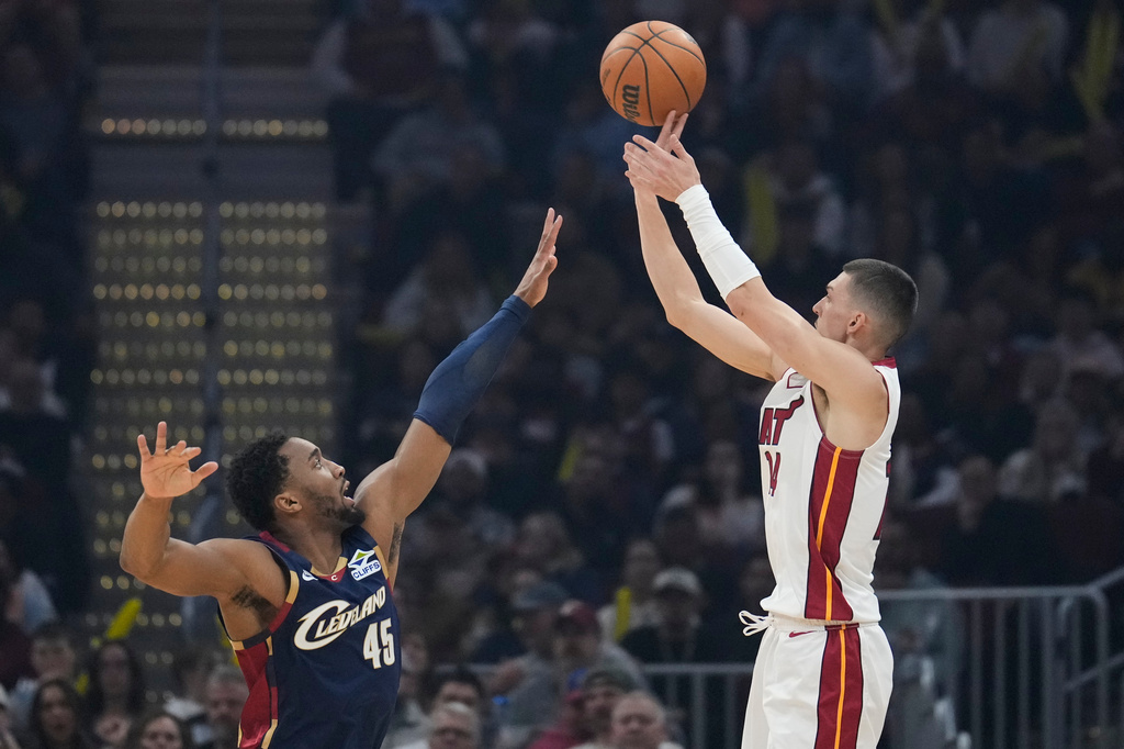 Miami Heat guard Tyler Herro, right, shoots over Cleveland Cavaliers guard Donovan Mitchell (45) in the first half of an NBA basketball game in Cleveland, Friday, March 27, 2026. (AP Photo/Sue Ogrocki)