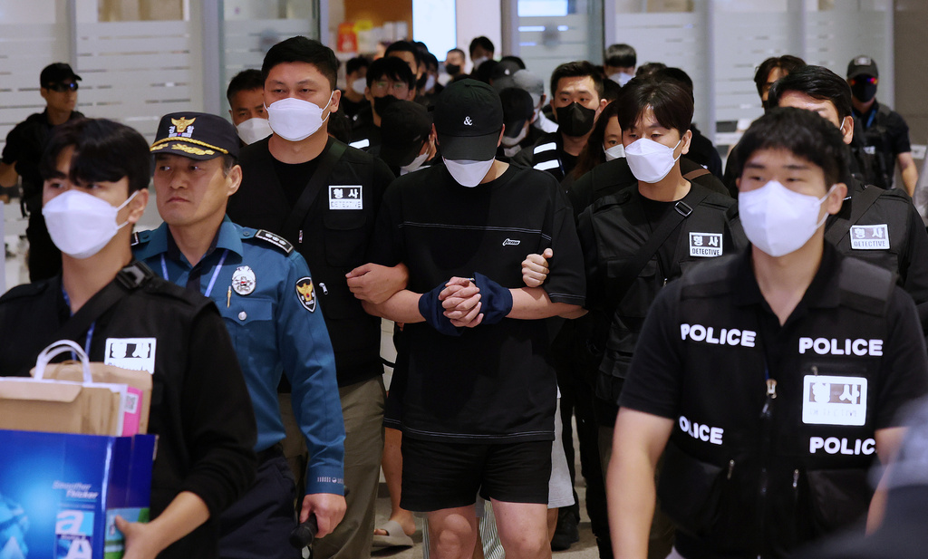 South Koreans, wearing caps, allegedly involved in online scams in Cambodia arrive at the Incheon International Airport, in Incheon, Saturday, Oct. 18, 2025. (Yonhap via AP)