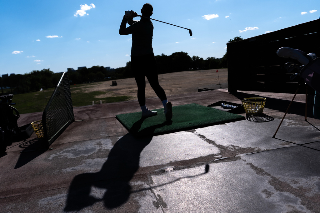 A golfer hits balls at the East Potomac Golf Course driving range, Sunday, May 3, 2026, in Washington. (AP Photo/Julia Demaree Nikhinson)