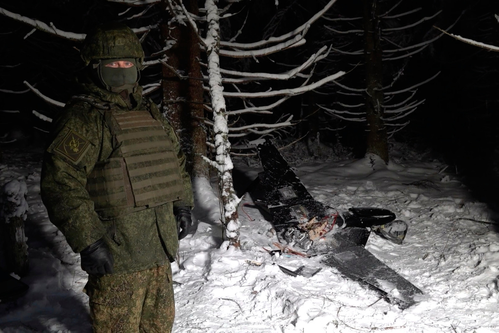 This image made from undated video provided by the Russian Defense Ministry Press Service on Wednesday, Dec. 31, 2025, shows a man in camouflage standing by a downed drone at an undisclosed location that it said was one of the Ukrainian drones involved in an alleged attack on a residence of President Vladimir Putin this week – a claim Kyiv has denied as a "lie". (Russian Defense Ministry Press Service via AP)