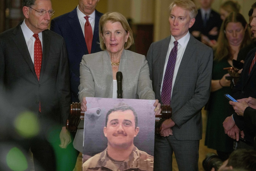 Sen. Shelley Moore Capito, R-W.Va., center, holds a photo of West Virginia Air National Guard Staff Sgt. Andrew Wolfe, as she is joined by from left: Sen. John Barrasso, R-Wyo., Senate Majority Leader John Thune, R-S.D., and Sen. James Lankford, R-Okla., during the Senate Republican policy luncheon news conference at the Capitol, Tuesday, Dec. 2, 2025, in Washington. (AP Photo/Rod Lamkey, Jr.)