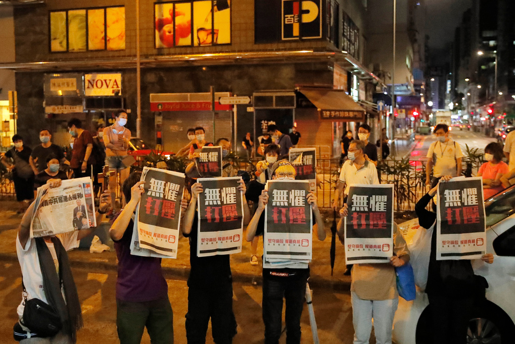 FILE -Supporters of Hong Kong media tycoon Jimmy Lai hold the copies of Apple Daily newspaper as Lai leaves a police station after being bailed out in Hong Kong, Wednesday, Aug. 12, 2020. (AP Photo/Kin Cheung, File)