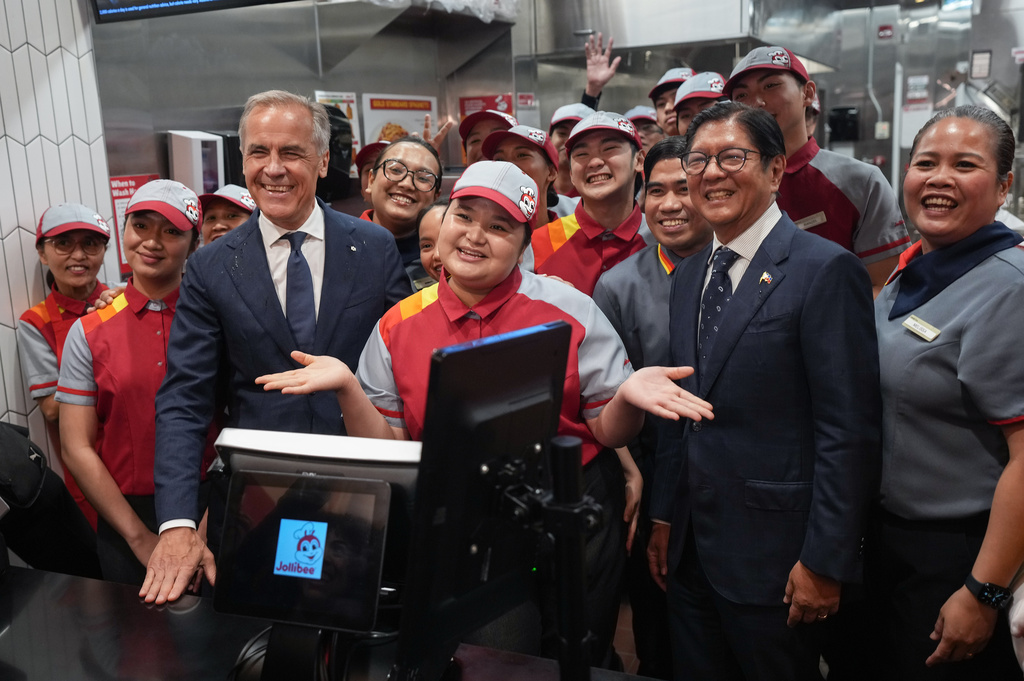 Canada's Prime Minister Mark Carney, left, and Philippines President Ferdinand Marcos Jr., right, pose with employees during a visit to a Jollibee fast food restaurant, in Vancouver, Thursday, July 2, 2026. (Darryl Dyck/The Canadian Press via AP)