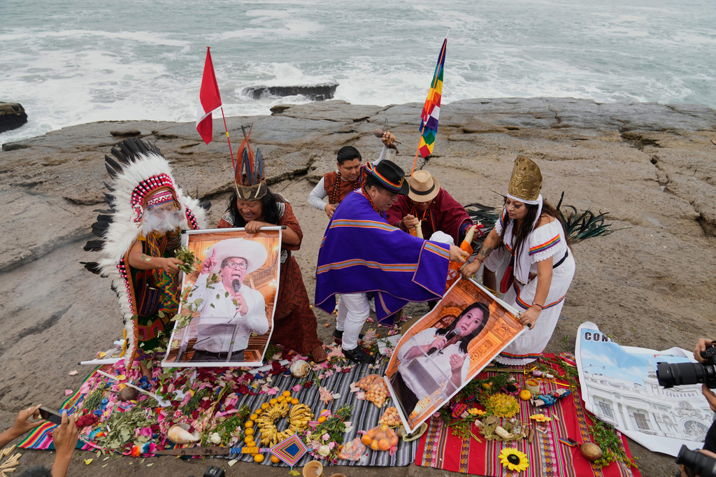 Shamans perform a ritual holding posters of presidential candidate Keiko Fujimori, right, and Roberto Sanchez on Herradura beach in Lima, Peru, Monday, June 1, 2026, ahead of their presidential runoff election. (AP Photo/Martin Mejia)