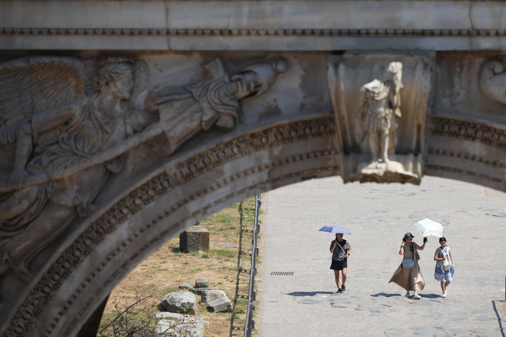Tourists use umbrellas for shade as they visit Rome's ancient Forum, Saturday, Aug. 1, 2026. (AP Photo/Alessandra Tarantino)