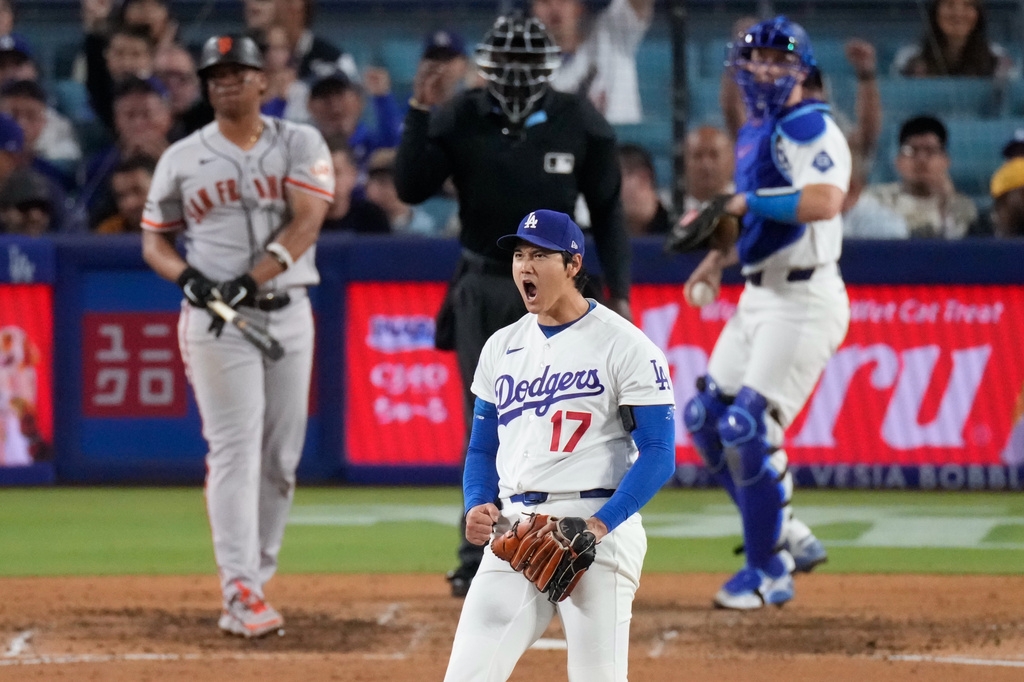 Los Angeles Dodgers two-way player Shohei Ohtani, center, reacts after striking out San Francisco Giants' Rafael Devers, left, as catcher Will Smith gets ready to throw the ball back during the sixth inning of a baseball game Wednesday, May 13, 2026, in Los Angeles. (AP Photo/Mark J. Terrill)