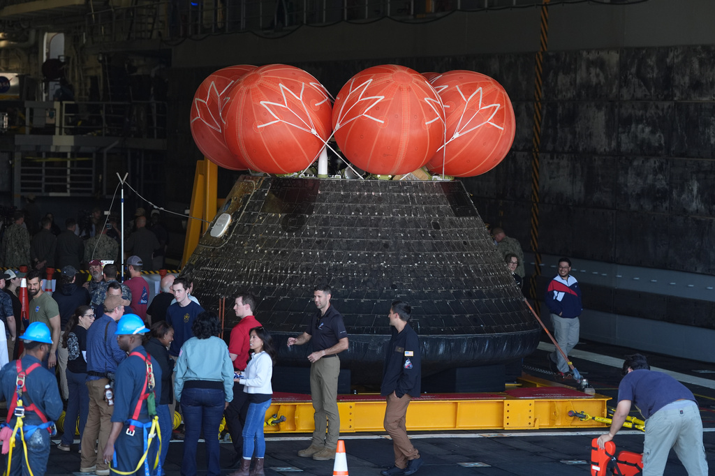 People gather around NASA's Artemis II capsule aboard the USS John P. Murtha at Naval Base San Diego Saturday, April 11, 2026, in San Diego. (AP Photo/Gregory Bull)
