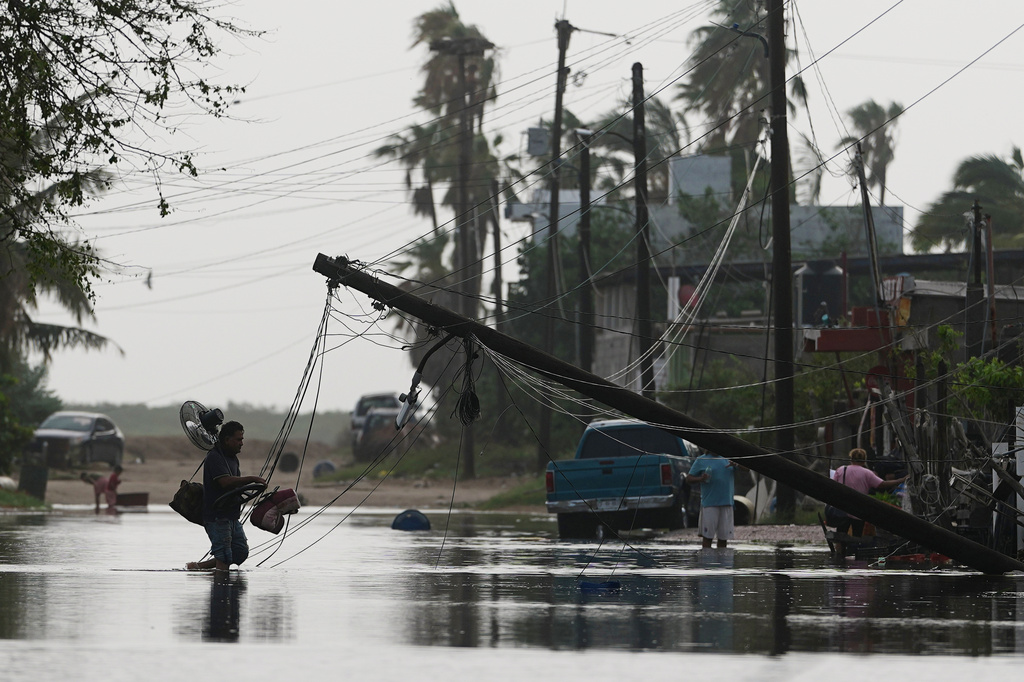 A man carries items through floodwater past downed electric lines after the passing of Hurricane Polo in Puerto San Carlos, Baja California Sur state, Mexico, Tuesday, Sept. 29, 2026. (AP Photo/Eduardo Verdugo)