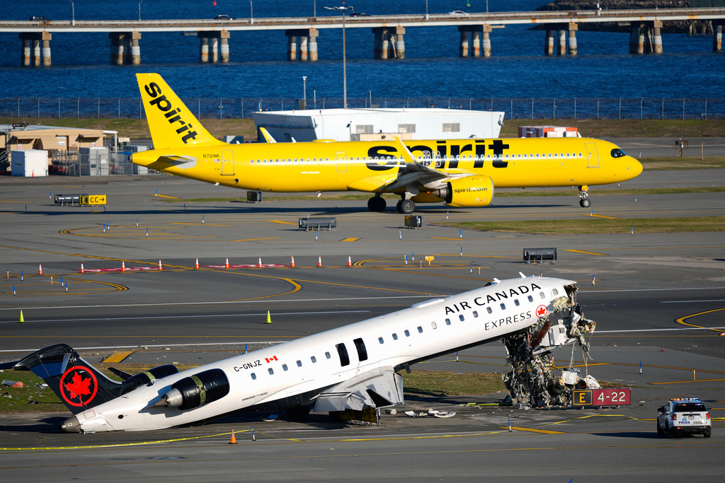 A Spirit Airlines jet taxis past an Air Canada Express jet sitting on the side of a runway, Tuesday, March 24, 2026, where it had collided with a Port Authority fire truck Sunday night at LaGuardia Airport in New York. (AP Photo/Yuki Iwamura)