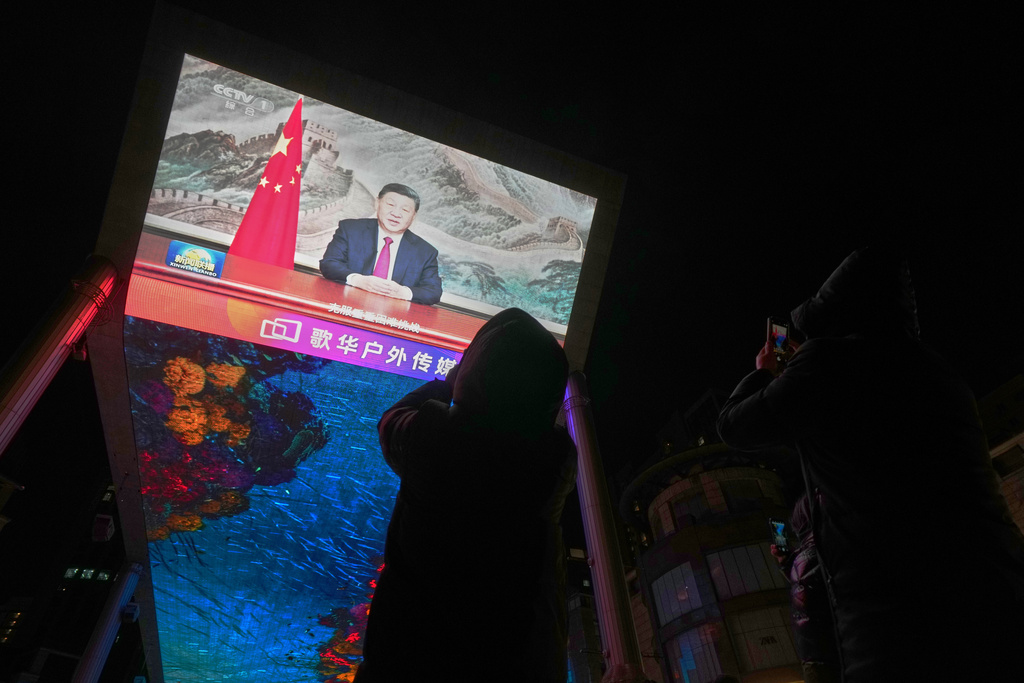 Residents use their smartphones to film a large screen at a shopping mall showing CCTV broadcasting Chinese President Xi Jinping delivering his 2026 New Year message, in Beijing, Wednesday, Dec. 31, 2025. (AP Photo/Andy Wong)