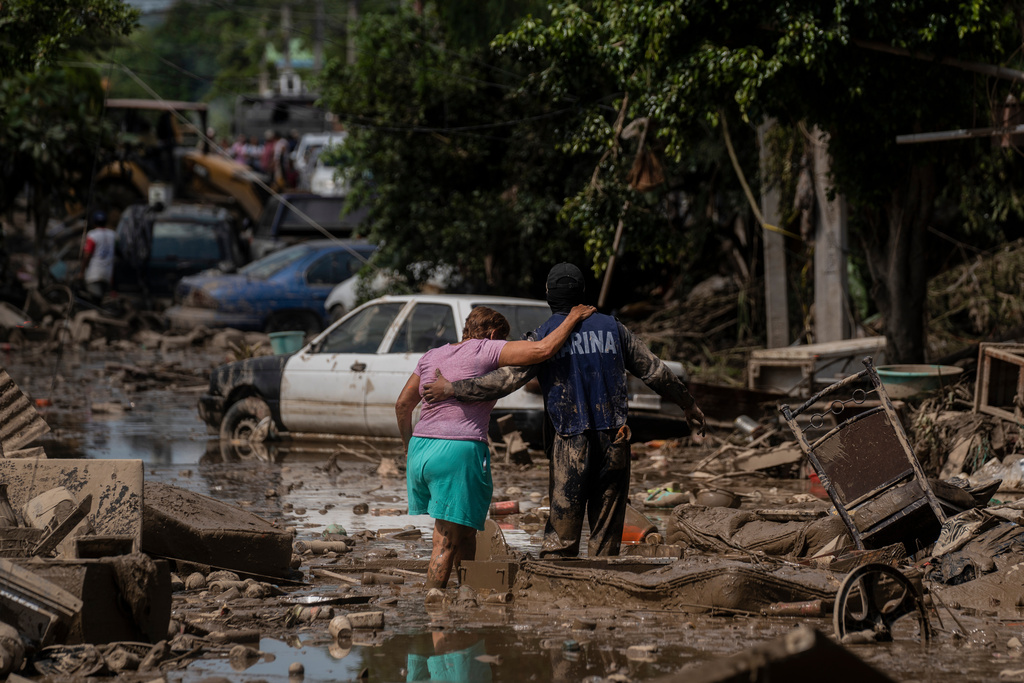 A Marine helps a woman cross a flooded street in Poza Rica, Veracruz state, Mexico, Sunday, Oct. 12, 2025. (AP Photo/Felix Marquez)