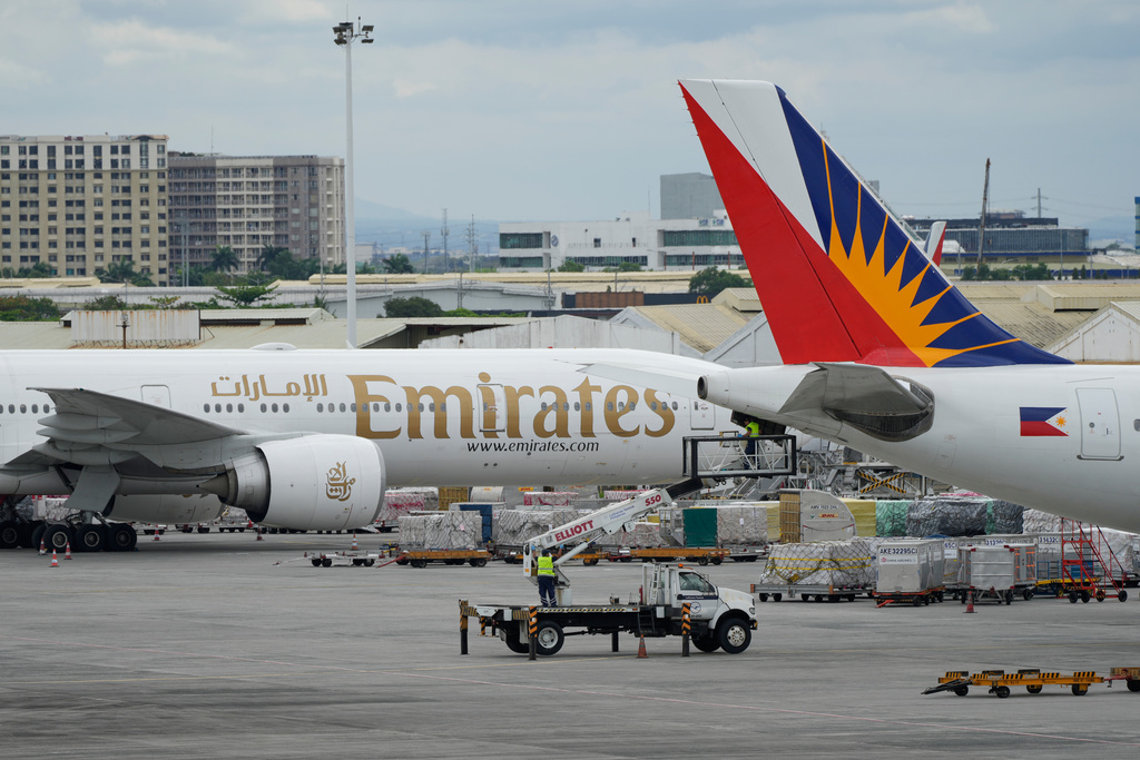 A man works beside a parked Emirates plane at Manila's International Airport, Philippines on Monday, March 2, 2026. (AP Photo/Aaron Favila)