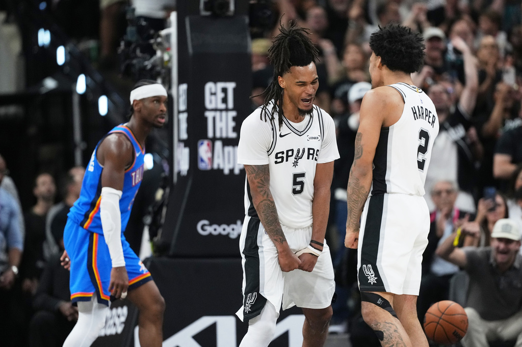San Antonio Spurs guard Stephon Castle (5) and guard Dylan Harper, right, react after a basket as Oklahoma City Thunder guard Shai Gilgeous-Alexander, left, looks on during the second half of Game 4 in the Western Conference finals NBA basketball playoffs series in San Antonio, Sunday, May 24, 2026. (AP Photo/Eric Gay)