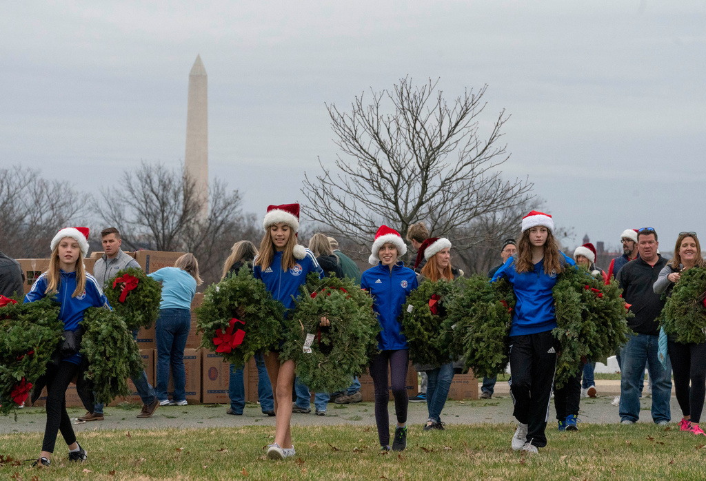 FILE - Volunteers walk with holiday wreaths to lay at headstones in Arlington National Cemetery during Wreaths Across America Day in Arlington, Va., Dec. 18, 2021. (AP Photo/Gemunu Amarasinghe, File)