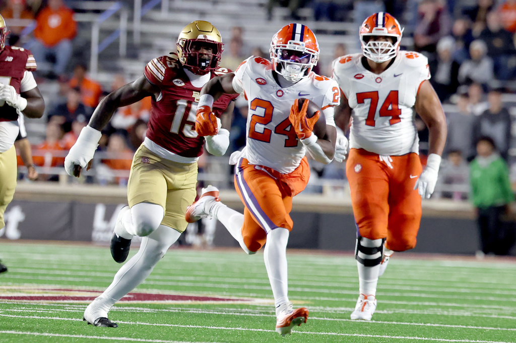 Clemson running back David Eziomume (24) runs for yardage while being chased by Boston College defensive end Quintavious Hutchins (15) during the second half of an NCAA college football game Saturday, Oct. 11, 2025 in Boston. (AP Photo/Mark Stockwell)