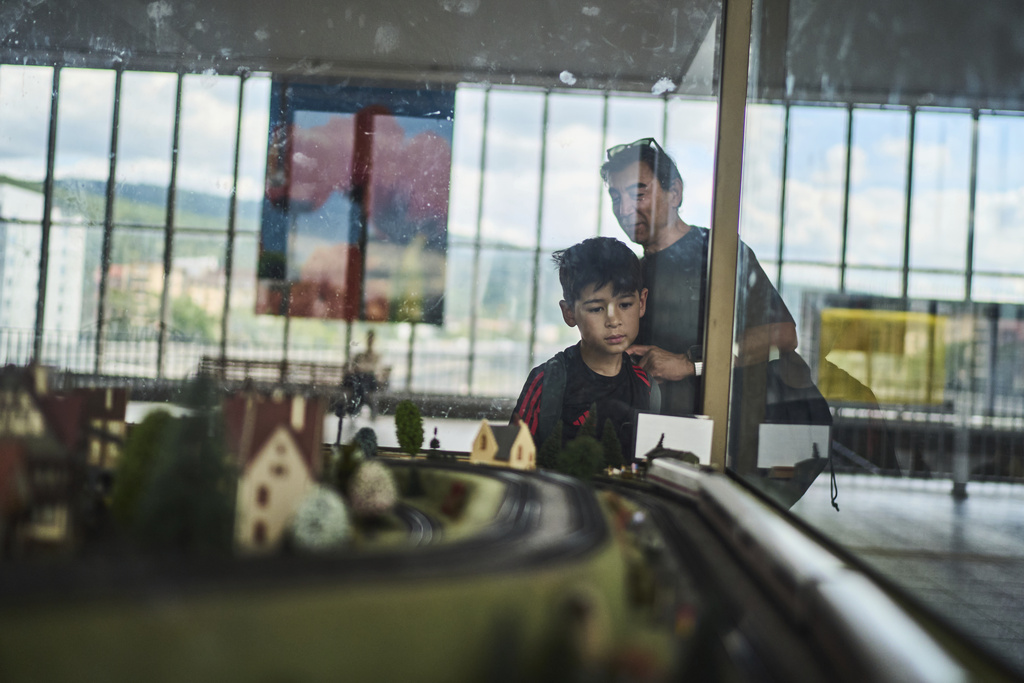 Former Xinjiang government engineer Nureli Abliz, rear, and his son, Ilyon, 9, stop to admire a model train scene on the way to see a dentist in Heidelberg, Germany, where they now live in exile, Wednesday, July 23, 2025. (AP Photo/David Goldman)