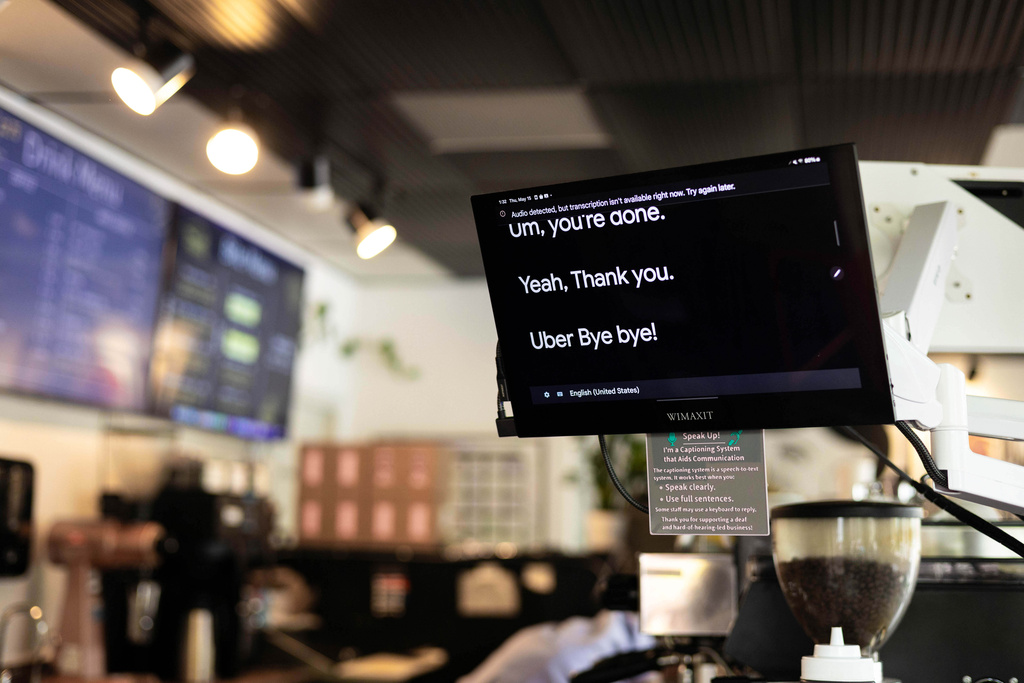 A screen displays words spoken by customers that comes from microphones translated onto screens is seen at the Woodstock Cafe on May 15, 2025, in Portland, Ore. (Allison Barr/The Oregonian via AP)