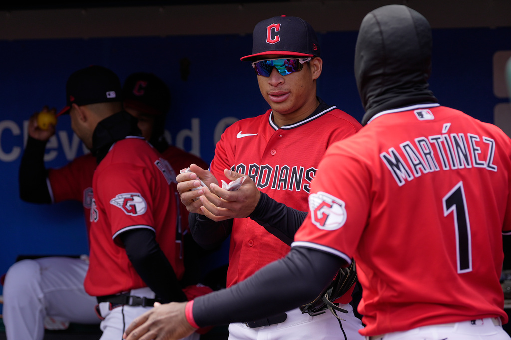 Cleveland Guardians Juan Brito, left, holds hand warmers in the dugout as he talks with center fielder Angel Martínez (1) in the dugout before a baseball game against the Kansas City Royals in Cleveland, Tuesday, April 7, 2026. (AP Photo/Sue Ogrocki)