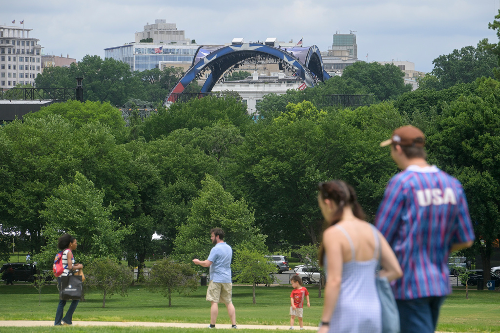 People walk near the Washington Monument as workers continue building the stage for a future UFC fight, seen top center, on the South Lawn of the White House, Monday, June 8, 2026, in Washington. (AP Photo/Rod Lamkey, Jr.)