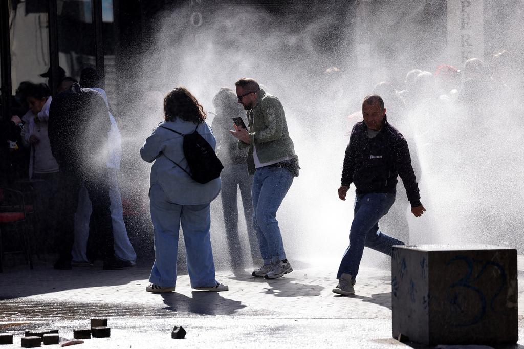 Protesters run from water sprayed by police water cannons during an anti-government demonstration outside the Education Ministry, in Tirana, Albania, Saturday, Oct. 17, 2026. (AP Photo/Hameraldi Agolli)