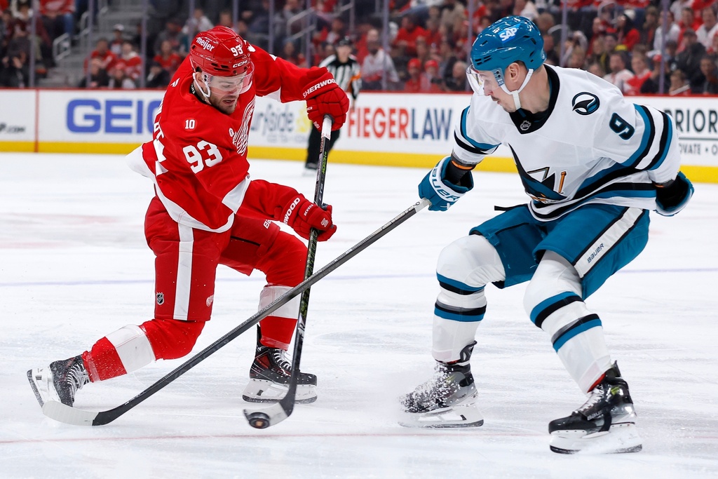 Detroit Red Wings right wing Alex DeBrincat (93) shoots on goal against San Jose Sharks defenseman Dmitry Orlov (9) during the first period of an NHL hockey game Friday, Jan. 16, 2026, in Detroit. (AP Photo/Duane Burleson)