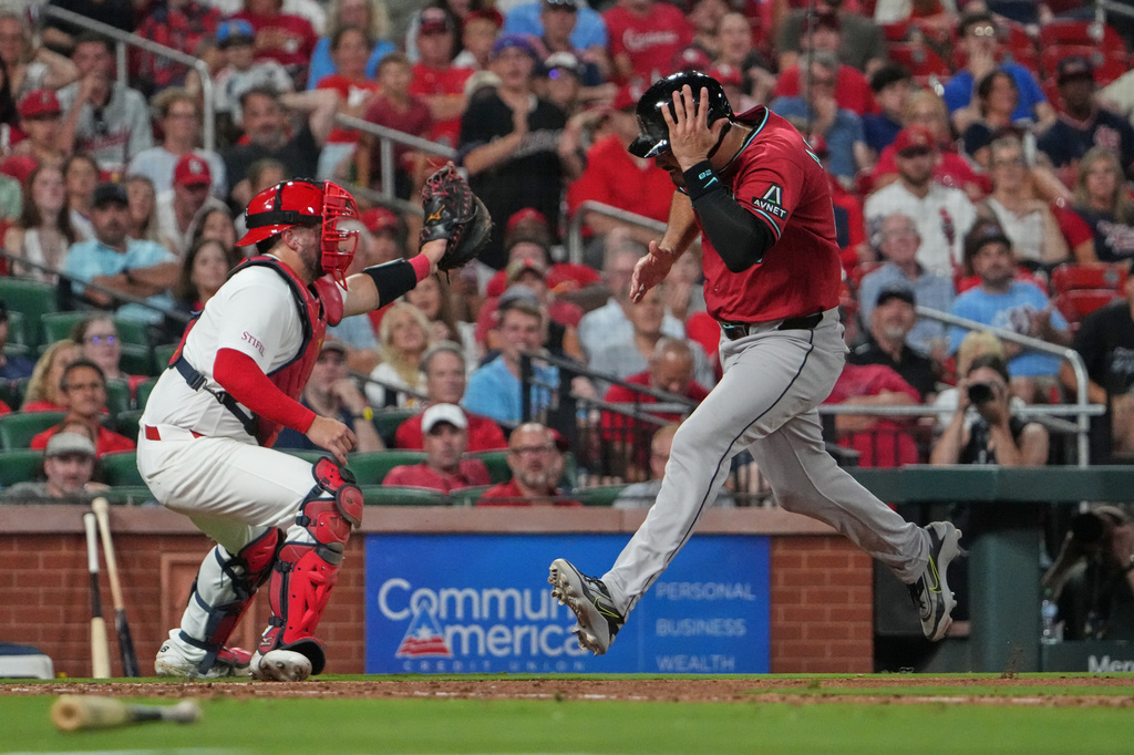 Arizona Diamondbacks' Nolan Arenado, right, scores past St. Louis Cardinals catcher Pedro Pagés during the ninth inning of a baseball game Tuesday, June 23, 2026, in St. Louis. (AP Photo/Jeff Roberson)