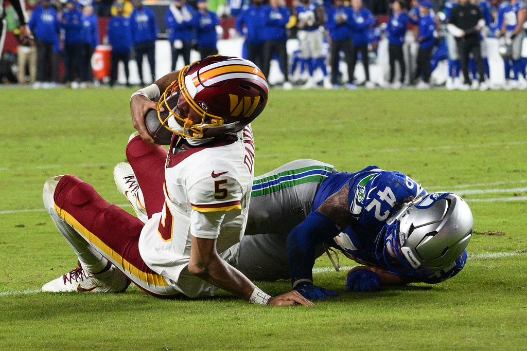 Washington Commanders quarterback Jayden Daniels (5) injures his arm as he is tackled by Seattle Seahawks linebacker Drake Thomas (42) during the second half of an NFL football game, Sunday, Nov. 2, 2025, in Landover, Md. (AP Photo/Nick Wass)