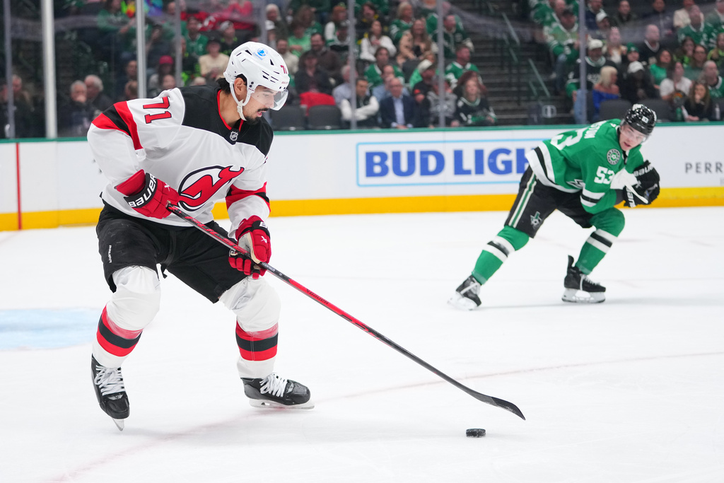 New Jersey Devils defenseman Jonas Siegenthaler (71) skates with the puck as Dallas Stars center Wyatt Johnston (53) looks on during the first period of an NHL hockey game Tuesday, March 24, 2026, in Dallas. (AP Photo/Julio Cortez)