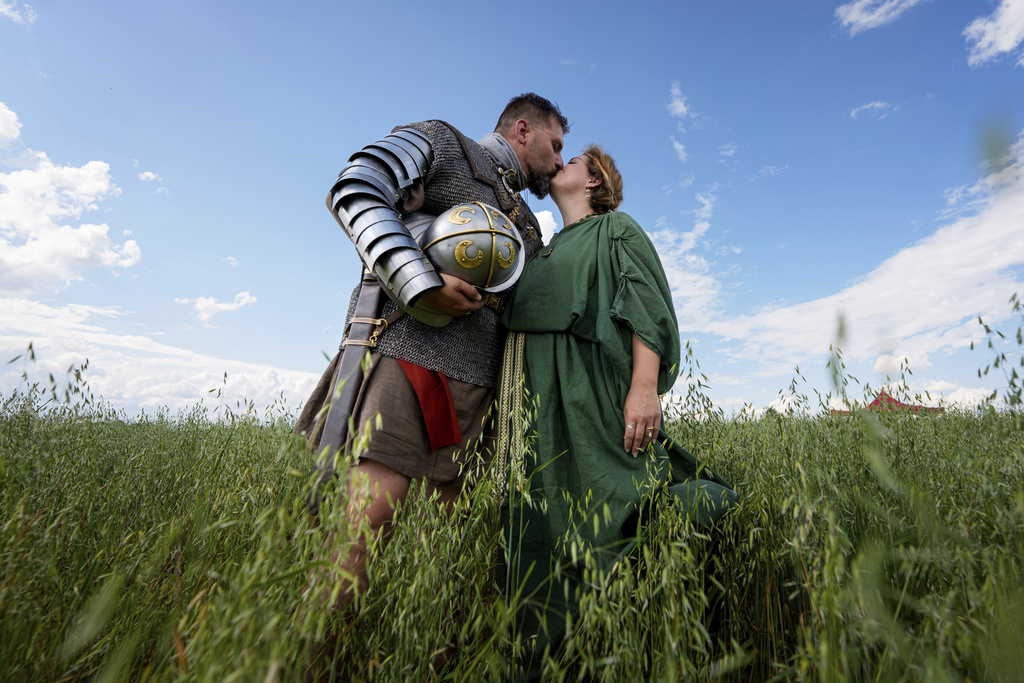 Andrej Miklanek of the Legio X Gemina Coh II, Roman era military historical group with members from the Czech Republic and Slovakia, kisses Valeria Terezia Danciakova after posing for a photograph in Poiana, Romania, Saturday, July 12, 2025, during the Getodava historical reenactment festival. (AP Photo/Andreea Alexandru)