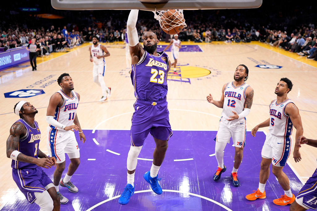 Los Angeles Lakers forward LeBron James, center, dunks as forward Jarred Vanderbilt, left, watches along with Philadelphia 76ers forward Justin Edwards, second from left, forward Trendon Watford, second from right, and guard Quentin Grimes during the first half of an NBA basketball game Thursday, Feb. 5, 2026, in Los Angeles. (AP Photo/Mark J. Terrill)