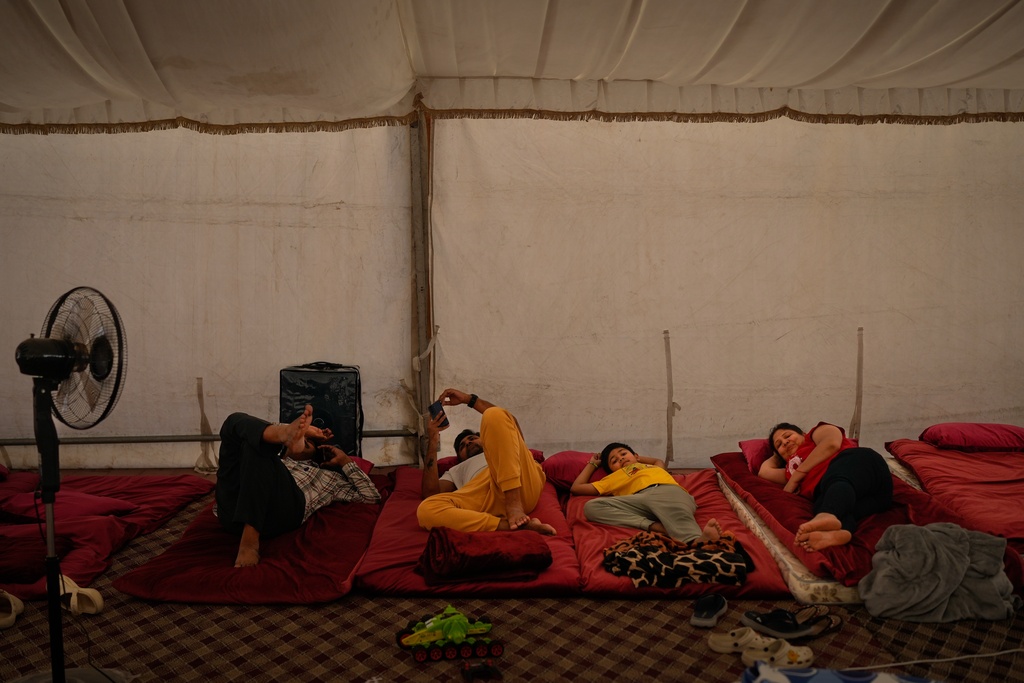 Stranded Indian travelers lie down inside a tent at a farmhouse owned by an Indian businessman, now converted into a shelter in Ajman, near Dubai, United Arab Emirates, Saturday, March 7, 2026. (AP Photo/Altaf Qadri)