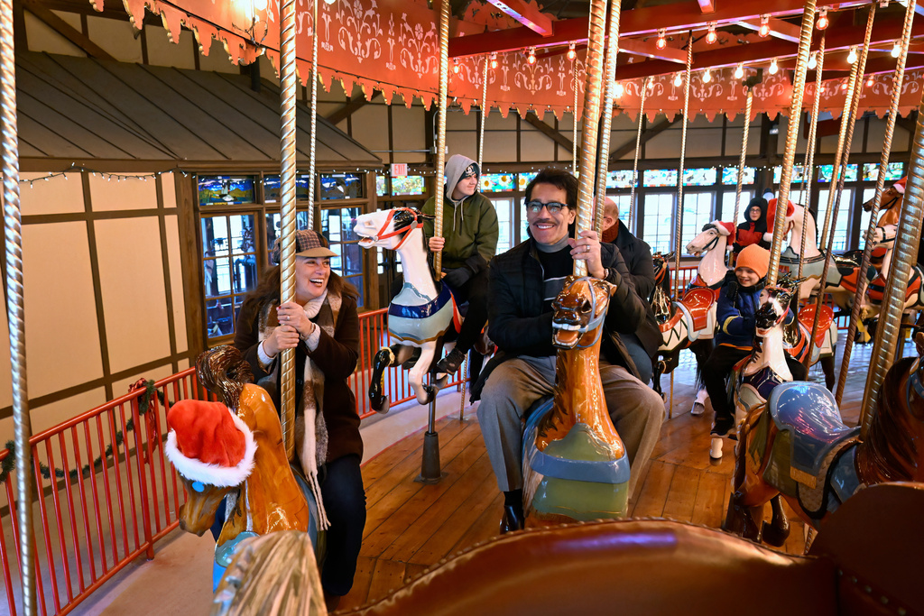 Christina and Raul Nieves of Windsor Locks ride the Bushnell Park Carousel in Hartford, Conn., Friday, Dec. 5, 2025. Scenes from the Hallmark movie "Ghost of Christmas Always" were filmed at the carousel. (AP Photo/Jessica Hill)