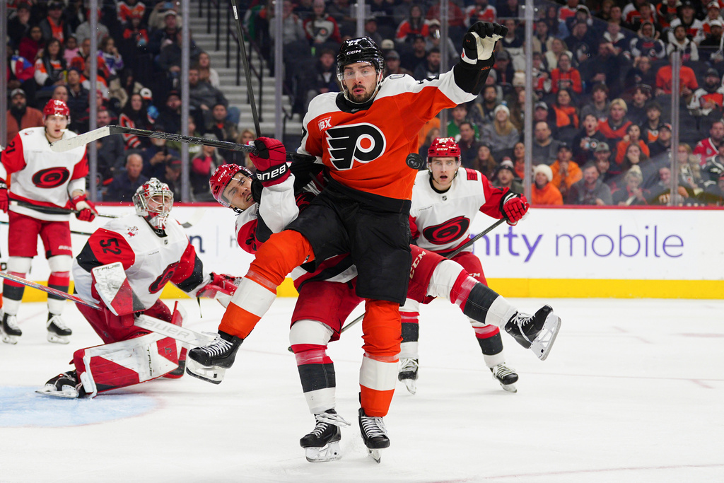 Philadelphia Flyers' Noah Cates, front, collides with Carolina Hurricanes' Logan Stankoven as they battle for the puck during the second period of an NHL hockey game, Saturday, Dec. 13, 2025, in Philadelphia. (AP Photo/Derik Hamilton)