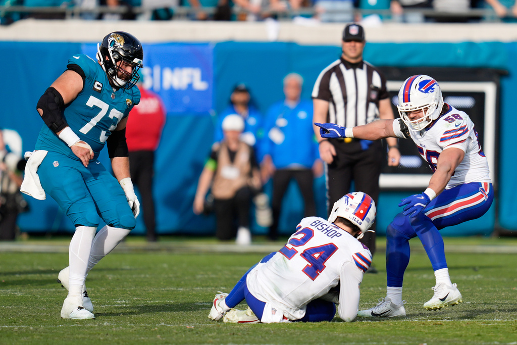Buffalo Bills safety Cole Bishop (24) intercepts a pass by Jacksonville Jaguars quarterback Trevor Lawrence, not visible, as teammate linebacker Matt Milano (58) and Jaguars center Robert Hainsey (73) look on during the second half of an NFL wild-card playoff football game Sunday, Jan. 11, 2026, in Jacksonville, Fla. (AP Photo/John Raoux)