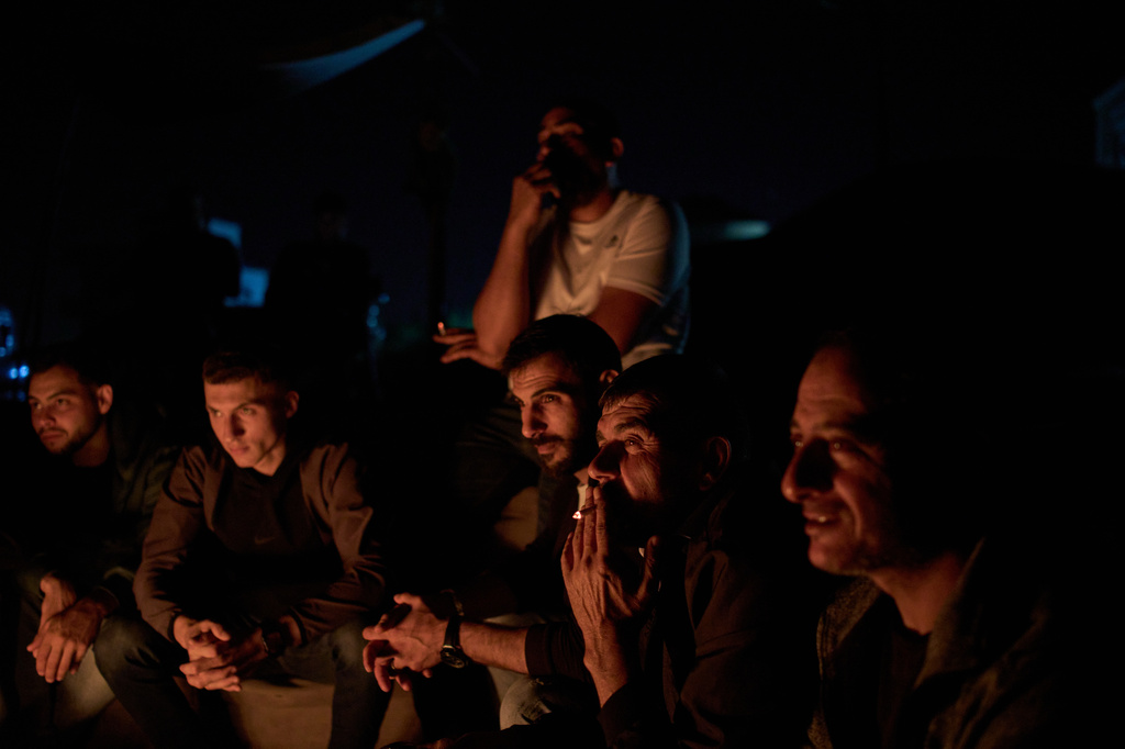 Palestinians sit next to the bonfire as they take part in a night watch to guard against Israeli settler attacks in the West Bank village of Sinjil, Thursday, July 16, 2026. (AP Photo/Leo Correa)