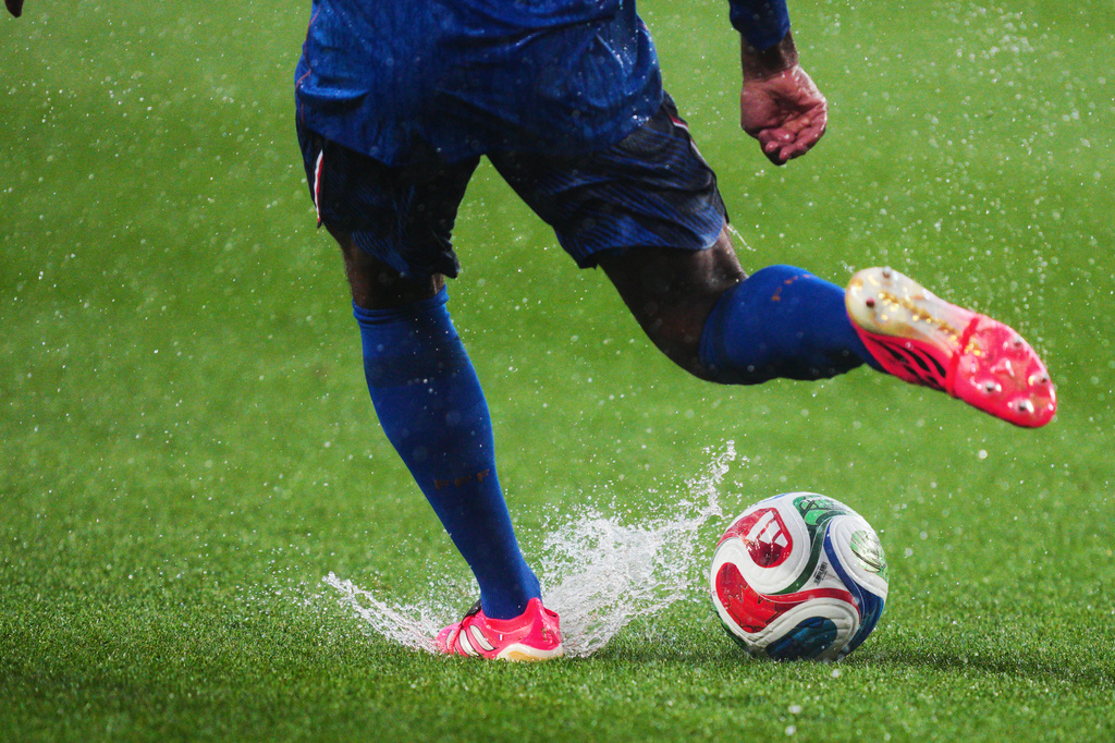 France's Jules Kounde (5) kicks the ball as water splashes on the pitch following a weather delay in the World Cup Group I soccer match between France and Iraq in Philadelphia, Monday, June 22, 2026. (AP Photo/Derik Hamilton)