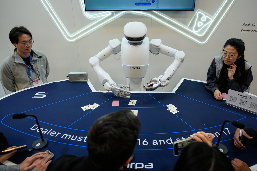 People watch as the Sharpa North robot deals poker at the Sharpa booth during the CES tech show Wednesday, Jan. 7, 2026, in Las Vegas. (AP Photo/John Locher)