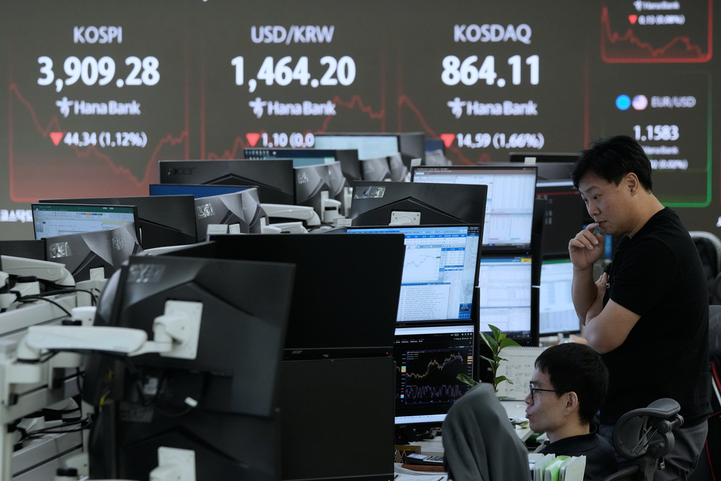 Currency traders watch monitors near a screen showing the Korea Composite Stock Price Index (KOSPI), top left, and the foreign exchange rate between U.S. dollar and South Korean won at the foreign exchange dealing room of the Hana Bank headquarters in Seoul, South Korea, Wednesday, Nov. 19, 2025. (AP Photo/Ahn Young-joon)