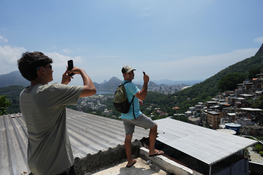 Paraguayan tourist Jose Martinez takes photos of his uncle Oscar Jara on a rooftop in the Rocinha favela, as Rio de Janeiro recorded a record number of international tourists in 2025, Tuesday, Jan. 27, 2026. (AP Photo/Silvia Izquierdo)