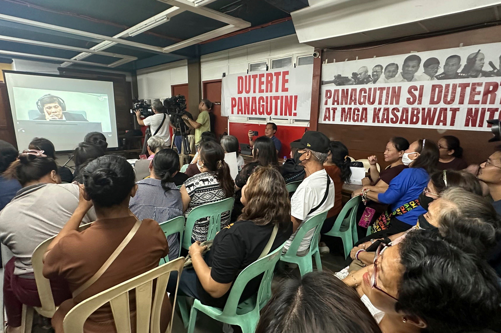 In this photo taken with a smartphone, former Philippine President Rodrigo Duterte is seen on screen attending a hearing at the International Criminal Court, as families of victims of killings linked to his administration's war on drugs and rights violations watch the proceedings in Manila, Philippines, Wednesday, Sept. 16, 2026. (AP Photo/Joeal Calupitan)
