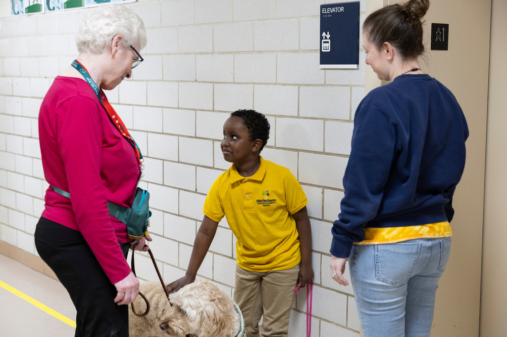 Second grader Samuel stops in the hallway to pet Sage, a therapy dog who visits Valley View Elementary weekly with her owner Linda Buchs-Hammonds, on April 29, 2026, in Columbia Heights, Minn. (Ellen Schmidt/MinnPost via AP)
